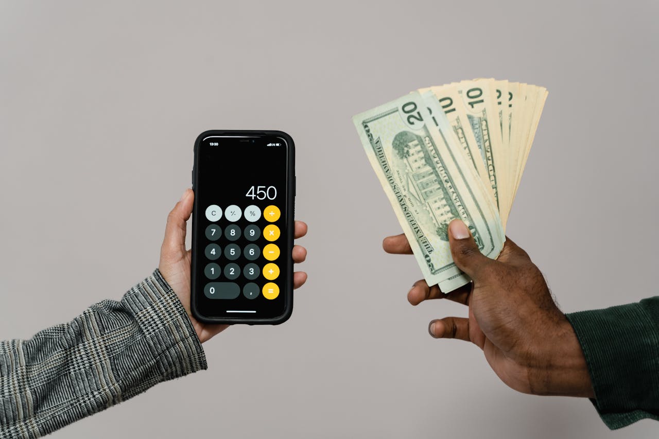 about-01 Two hands displaying cash and a smartphone calculator with a digital display, indicating a financial transaction.