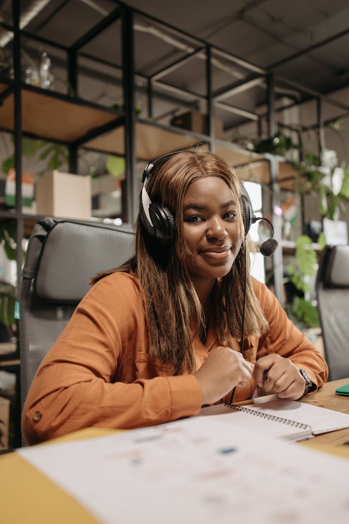 who-we-are-img Smiling call center agent with headphones working indoors, sitting at a desk.