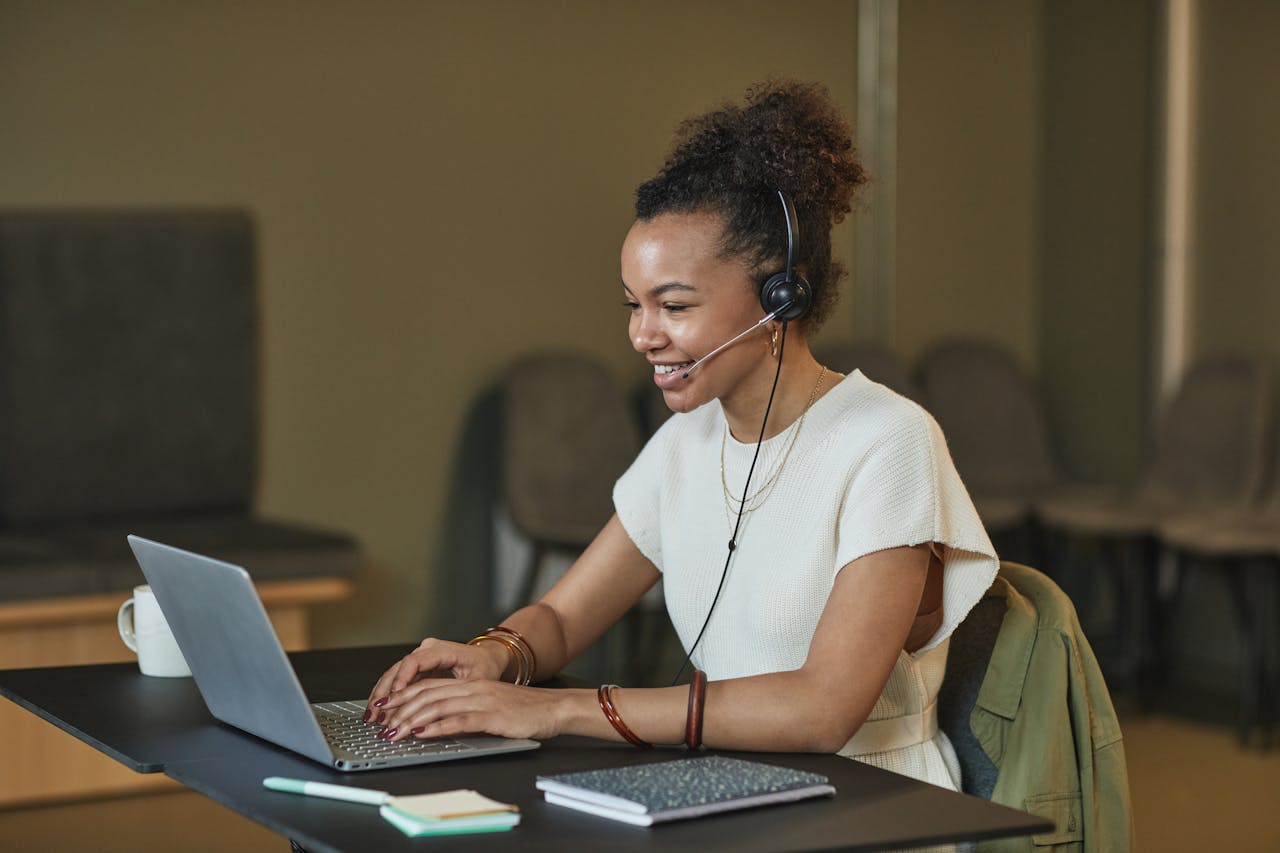 mission-img African American woman in a call center setting, working on a laptop and wearing a headset.